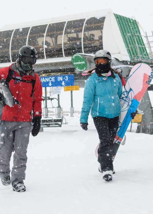 Snowboarders walking past the Cairnwell chair in snow